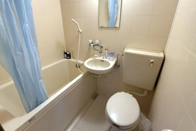 プライバシーが守られる寮個室内のユニットバスの画像。トイレ、洗面台、浴槽がセットになった清潔な水回り。