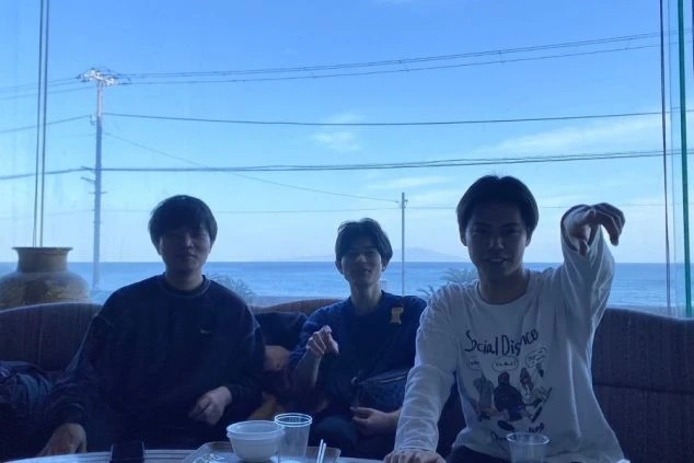 海を一望できるホテルのロビーで、窓の外を指さしながらくつろぐリゾートバイト仲間のワクトリスタッフたちの画像。