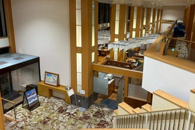 ホテルのの広々とした吹き抜けのロビーと階段。山中湖を一望できるリゾートホテルでの、フロント・レストラン・接客のリゾートバイト求人イメージ。