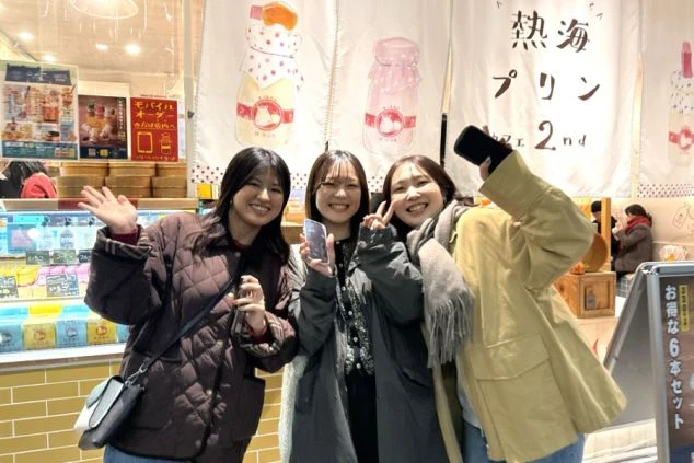 「熱海プリンカフェ 2nd」の店内で、笑顔でポーズをとる3人の若い女性。