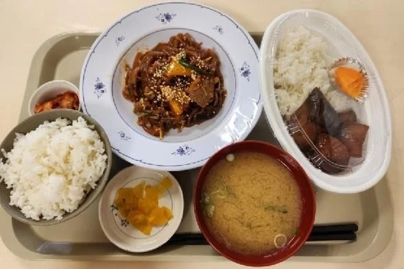 トレーに載った、白飯、チャプチェ風の炒め物、魚の煮付け、味噌汁、キムチ、漬物の定食。