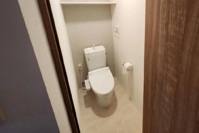 白い壁と床のシンプルな空間に、温水洗浄機能付きの洋式トイレ。