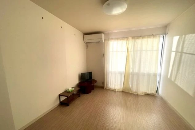 リゾートバイト完全個室寮の室内。エアコン、テレビ、机が完備された綺麗な洋室で、日当たりも良く快適な住空間。