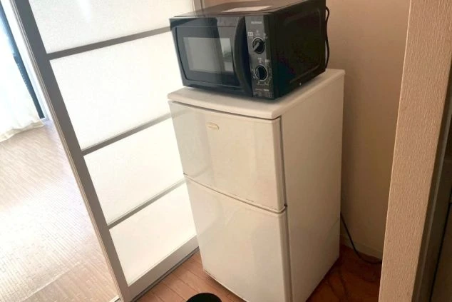 リゾートバイト寮の生活家電。2ドア冷蔵庫と電子レンジが室内に完備され、一人暮らしをすぐに始められる設備。