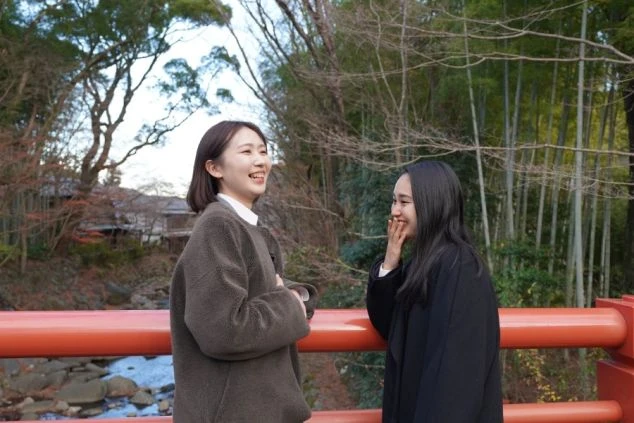 修善寺の竹林を背景に、朱塗りの橋の上で笑顔で会話を楽しむ女性ワクトリスタッフたちの画像。