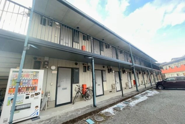 リゾートバイト住み込み求人の個室寮外観。アパートタイプで各室が独立しており、敷地内に自販機もある便利な環境。