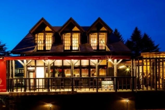 夜のライトアップが美しい軽井沢のハーフティンバー様式ペンション。ダイニングバーを併設したおしゃれな施設でのリゾートバイト求人イメージ。