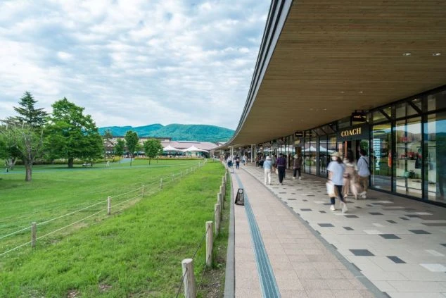 長野県軽井沢町にある「軽井沢・プリンスショッピングプラザ」の広大な芝生エリアとショップ。休日にショッピングを楽しめる、軽井沢エリアでの住み込みリゾートバイトの生活環境イメージ。