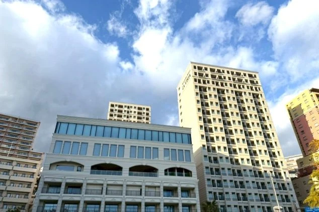 熱海市街にそびえ立つリゾートホテルの外観。青空を背景に、モダンで洗練された高層のホテル建築が写っている。