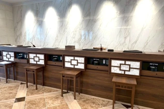 リゾートホテルのフロントカウンターのイメージ画像。大理石風の壁面と木目調のカウンターが組み合わさった、高級感と落ち着きのある受付スペース。