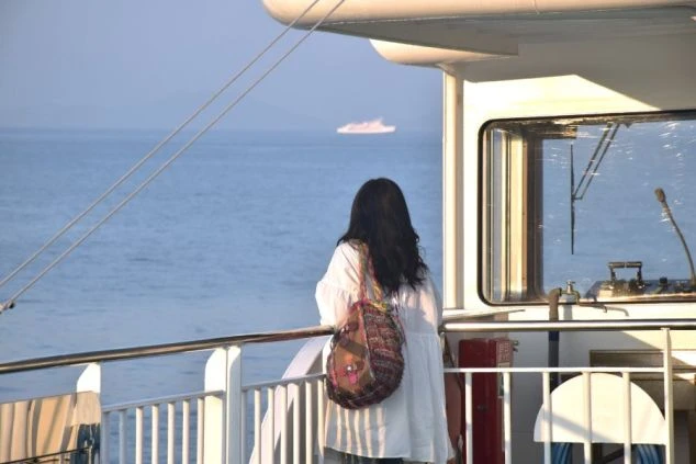 香川県・小豆島へ向かうフェリーのデッキから瀬戸内海を眺める女性の画像。