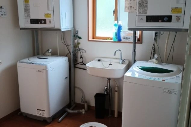 リゾートバイト寮の洗濯・乾燥機設備。共用スペースに完備され、日々の生活もスムーズで便利な環境。
