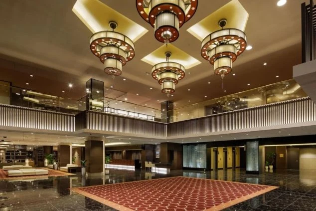 豪華なホテルのロビーラウンジ。高い吹き抜けの天井からは、和モダンなデザインの大きなシャンデリアが複数吊るされている。