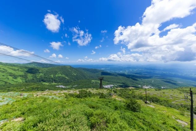 那須ロープウェイ付近から見下ろす、青空と緑豊かな山々のパノラマ風景。