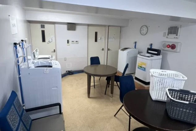 リゾートバイトの寮にある、広々とした共用ランドリールーム。洗濯機が複数あるほか、テーブルと椅子も置かれ、仲間との交流の場にもなっています。