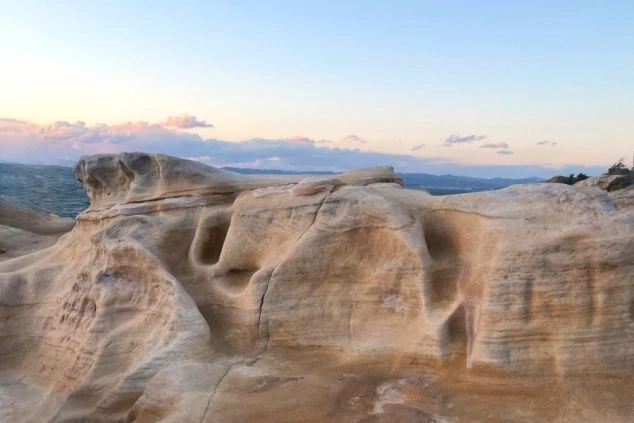 南紀白浜の景勝地「千畳敷（せんじょうじき）」の広大な畳畳岩の画像。打ち寄せる波と夕暮れの空が美しい、和歌山のリゾートバイトスタッフに人気の散策コース。