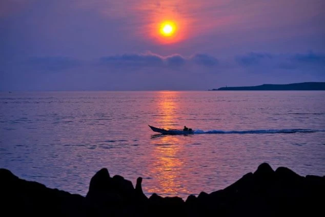 礼文島の海をオレンジ色に染める美しい夕日と漁船。北海道の自然に囲まれたリゾートバイトの画像。