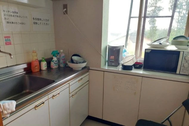 石造りの落ち着いた雰囲気の内湯。浴槽の縁は曲線を描いており、壁は質感のある岩肌のデザイン。窓からは柔らかな光が差し込んでいる。