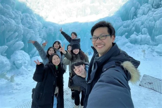 さっぽろ雪まつりの巨大な雪像前で笑顔でポーズをとるリゾートバイト仲間たち。休日の観光を楽しむ様子