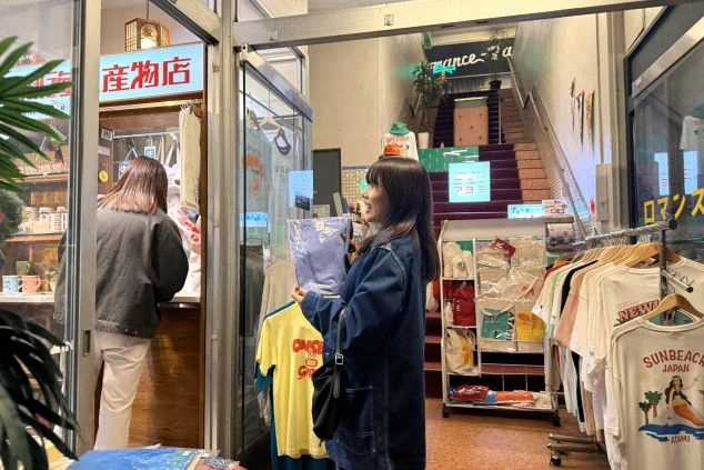 レトロな雰囲気のショップで、商品を手に取りながら笑顔で買い物を楽しむ女性。