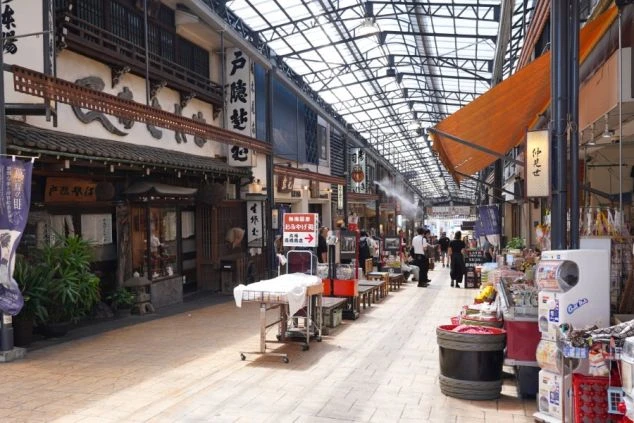 レトロな看板や商店が並ぶ、屋根付きの賑やかな商店街の通り。