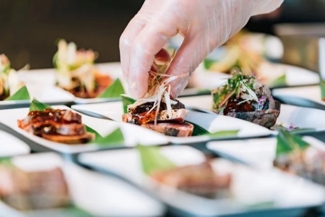 皿に盛り付けられた料理に、手際よく薬味を添える料理人の手元。