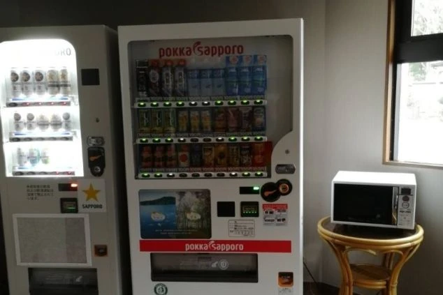 寮内の共用スペースにある自動販売機と電子レンジ。夜食や休憩時に便利な、リゾートバイト生活を支える設備。