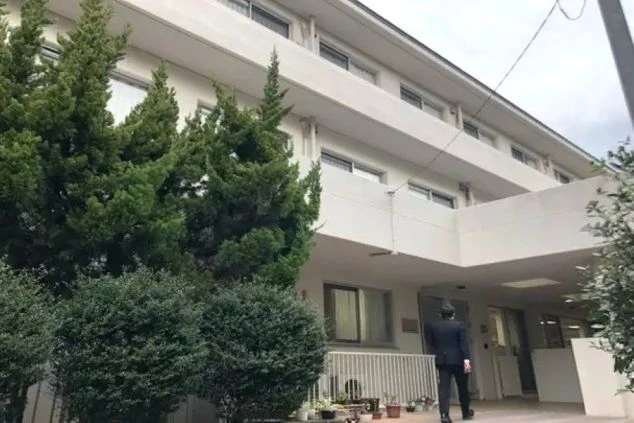 寮の外観。清潔感のある白い建物で、庭の緑が映えている。