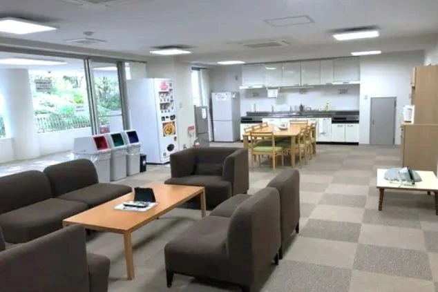 寮の共同キッチンと食堂。冷蔵庫や調理台、テーブル、ソファが置かれた広々とした空間。