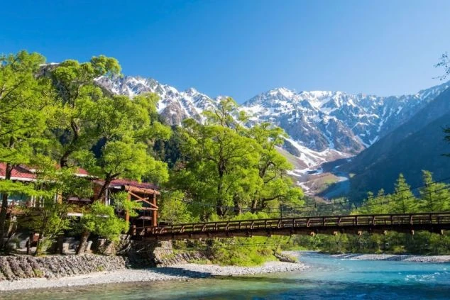 長野県・上高地の象徴「河童橋」と、残雪の北アルプス・穂高連峰を望む絶景の画像。