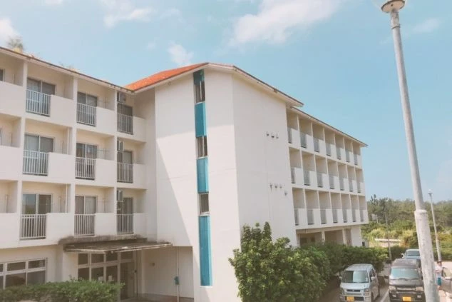 派遣スタッフが生活する住み込み寮の外観。青空の下に立つ、バルコニー付きの清潔感ある集合住宅。