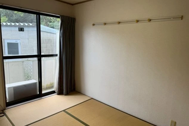 寮の個室。畳敷きの和室で、大きな窓とエアコンが完備。自分の布団で生活できるシンプルな部屋。