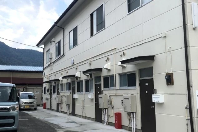 リゾートバイトの寮の外観画像。2階建てのアパートタイプで、各部屋に専用の玄関と給湯器が設置されている。