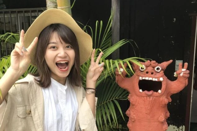 石垣島のシーサー像の横で笑顔でポーズをとる女性スタッフ。沖縄リゾートバイトならではの楽しい思い出。