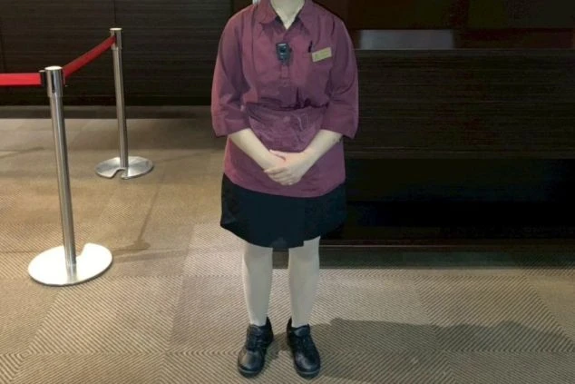 レストランで働く女性スタッフ。バーガンディ色のシャツに黒いスカートとエプロンを着用しており、レストランサービスやホール業務の仕事をアピール。