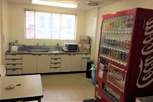 リゾートバイトの寮の共用キッチンの画像。シンクと電子レンジ、自動販売機が並び、共同生活の場として利用できる。