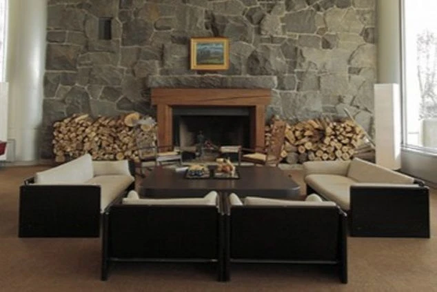 石壁の暖炉と薪が積まれた、落ち着いた雰囲気のモダンなラウンジスペース。