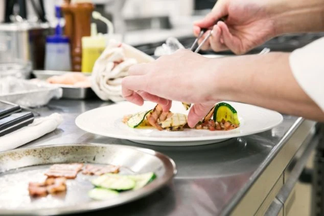 レストランの厨房で料理を盛り付ける調理スタッフ。リゾート地ならではの食材に触れられる調理リゾートバイト。