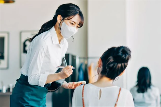 レストランで注文を取るホールスタッフの女性。笑顔でおもてなしを学ぶリゾートバイトの仕事風景。