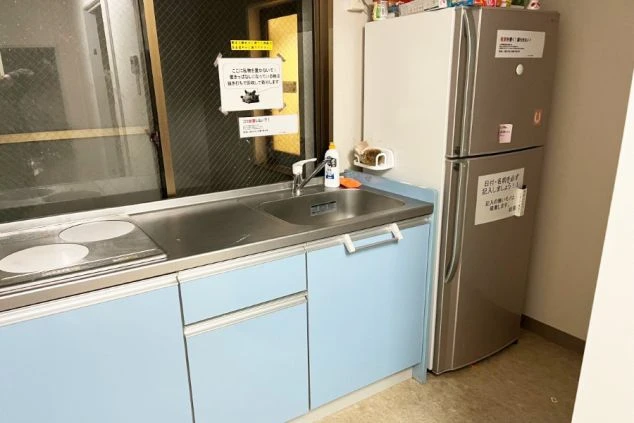 共用キッチン。ステンレス製のシンクと、2口の電磁調理器が備わったコンロ台が並んでいる。