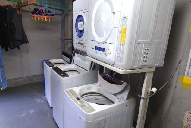 洗濯機と乾燥機が複数台設置された、寮の共同ランドリースペース。