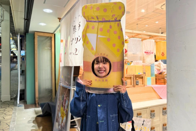 熱海プリンの顔出しパネルで笑顔を見せる女性。リゾートバイト先での楽しい思い出作りと観光地での生活。