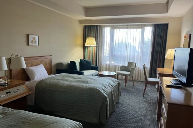 リゾートバイトの社員寮の部屋を表現するイメージ画像。ベッドが2つと、ソファやテレビが備え付けられた広々とした洋室。