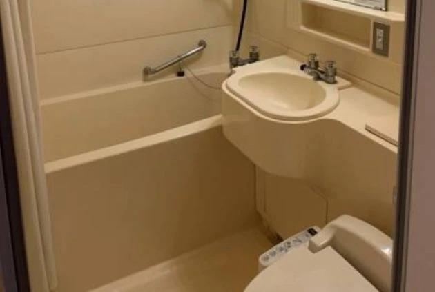 ユニットバスの内部を写した画像。バスタブと洗面台、トイレが一体になった、リゾートバイトの寮にあるバスルーム。
