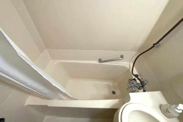 クリーム色のシンプルなユニットバスの俯瞰写真。浴槽と洗面台、温水洗浄便座付きのトイレが配置されている。