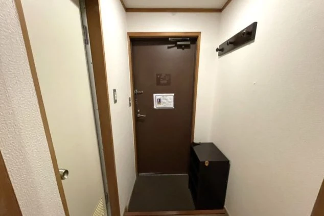 客室の入り口付近。茶色のドアの横には靴箱があり、壁にはハンガーラックが設置されている。