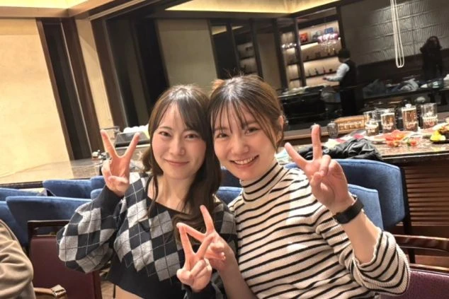 飲食店でピースサインをする女性2人の写真。落ち着いた雰囲気の店内で、共に働く仲間と交流を深めるひととき。