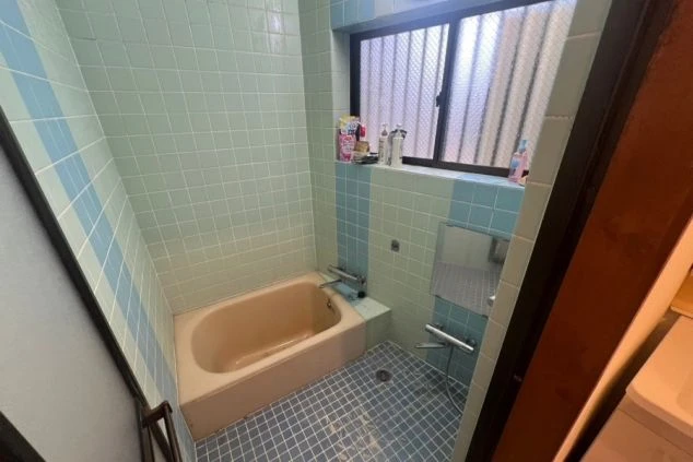 ワクトリの社員が出張で撮影した、リゾートバイトの寮の浴室の画像。水色のタイルが印象的な空間に、浴槽とシャワーが備え付けられている。窓があり、明るく清潔感がある。