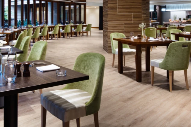 リゾートホテル内にある、北欧風のモダンなデザインが特徴的なレストランの画像。明るい黄緑色のベロア調チェアと木の温もりを感じるテーブルが並ぶ、広々とした清潔感あふれる空間。