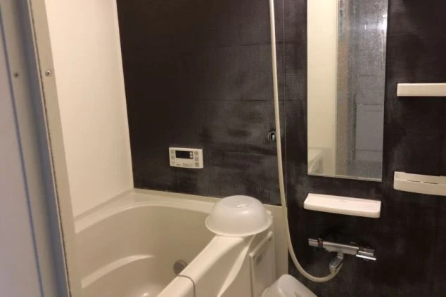 リゾートバイトの寮のバスルームの画像。バスタブが備え付けられており、壁にはシャワーが設置されている。リゾートバイトの寮の風呂場の画像。